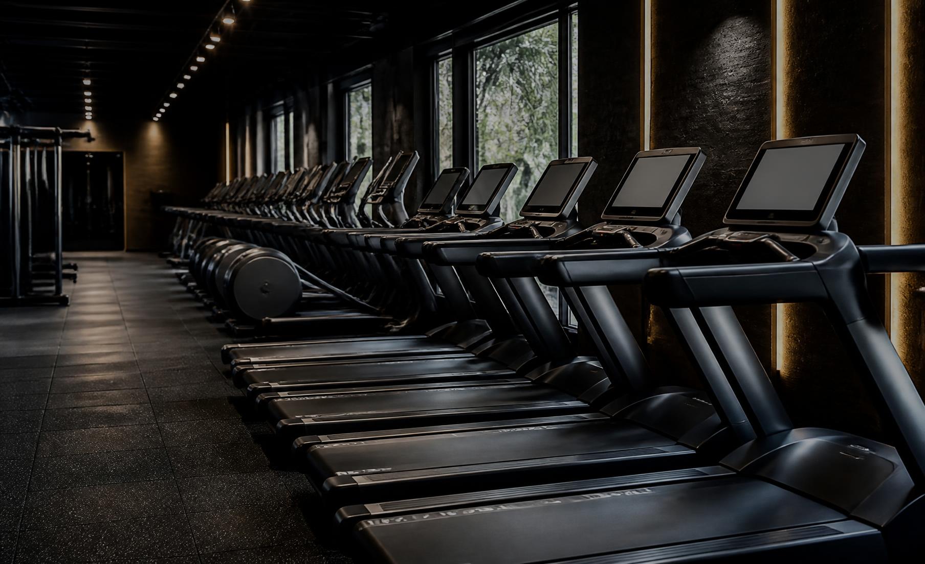 Row of premium commercial treadmills in a dark health club